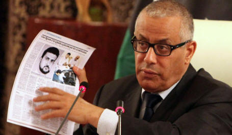 Libyan Prime Minister Ali Zidan holds up copies of foreign newspapers reporting the kidnapping of Abu Anas al-Libi by US special forces